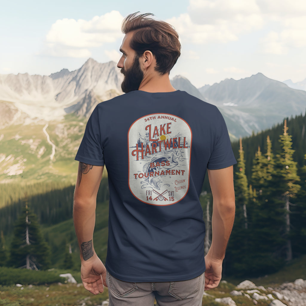 Back view of a man standing on mountain overlooking a valley wearing the Reelfly Outdoors Lake Hartwell Bass Tournament T-Shirt in the color Navy.