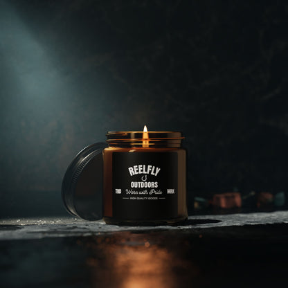 Reelfly Outdoors 4oz Trademark Candle sitting on table with dark surface in dim lighting